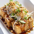 Tahu Tek-Tek: Fried tofu served with a peanut sauce dressing, topped with bean sprouts, cucumber, and shallots, often found in street food stalls. photo on white isolated background