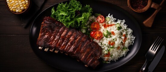 Canvas Print - A delicious dish consisting of black plate of ribs, rice, and vegetables on a wooden table. The perfect combination of red meat, staple food, and vegetable ingredients