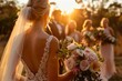 Warm sunset light bathes the bride in focus, with a bouquet, as the wedding party and guests are captured in the backdrop