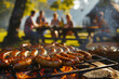 Sausages baking on the grill. In the background, people sitting at a table and eating a meal together.