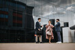 © qunica.com - Three professional colleagues are engaged in a passionate discussion about business strategies and teamwork, with a corporate building backdrop.