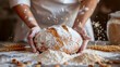 Close-up of baker's hands holding freshly baked bread, surrounded by flour and grains of wheat, home cooking and hobby, craft process, ingredients.