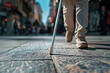 Blind person with a white cane walks along the sidewalk of a city street, focus on a white cane and legs, low-angle view