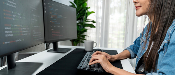 Wall Mural - Young Asian in IT developer creating with typing online information on pc with coding program data of website application, wearing jeans shirt. surrounded by safety analysis two screens. Stratagem.