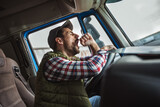 Fototapeta  - A tired truck driver takes a break from driving and rests in his truck