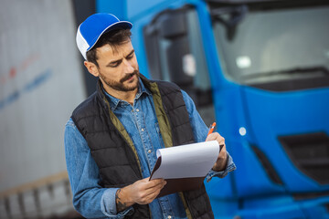 Wall Mural - Cargo dispatcher writing on clipboard on truck parking lot.