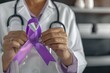 A woman in white lab coat holding a purple ribbon