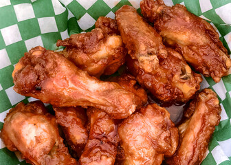 Wall Mural - Naked chicken buffalo wings in a basket with green and white checkered wax paper