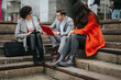 © qunica.com - Three business associates having a casual meeting on outdoor steps with documents and a digital tablet.