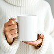 © Margo_Alexa - A woman in a white sweater holding up a coffee cup