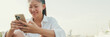 © Andrii Nekrasov - Smiling young woman using mobile phone on seascape background, Panorama