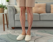 Woman suffering from pain in leg at home, closeup of legs