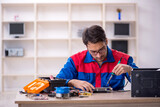 Fototapeta Kwiaty - Young male repairman repairing computer