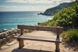 A lone wooden bench gazes upon the tranquil azure sea, providing a serene space for contemplation