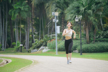 Wall Mural - asian woman jogger running in green nature public park.