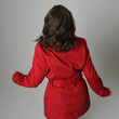 head and shoulders close up portrait of beautiful brunette woman model, wearing red trench coat jacket. isolated on white studio background, high angle perspective. back view, looking away.
