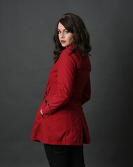 Wall Mural - close up portrait of beautiful brunette woman model, wearing red trench coat jacket. isolated on dark studio background with shadows.  back view, facing away from camera.