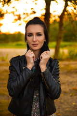 Wall Mural - Portrait of a beautiful dark-haired young woman, girl on a background of summer sunset and a green park.