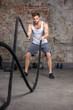 A man engaged in fitness and sports trains with ropes in the cross fit gym. Fitness, healthy lifestyle and gym workouts concept.