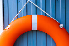 Orange Lifebuoy Hanging On The Wall, Door. Water Safety Concept.
