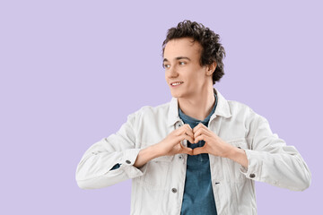 Wall Mural - Young man making heart with his hands on lilac background