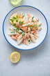 Blue and white plate with creamy salmon pasta, top view on a light-grey granite background, vertical shot with space