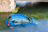 Fototapeta Uliczki - Blue vehicle drown in water canal. Extreme accident car sink in river pound lake, traffic incident