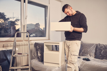 Wall Mural - Man working and assembling furniture in a new apartment.