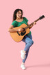 © Pixel-Shot - Young African-American woman playing acoustic guitar on pink background