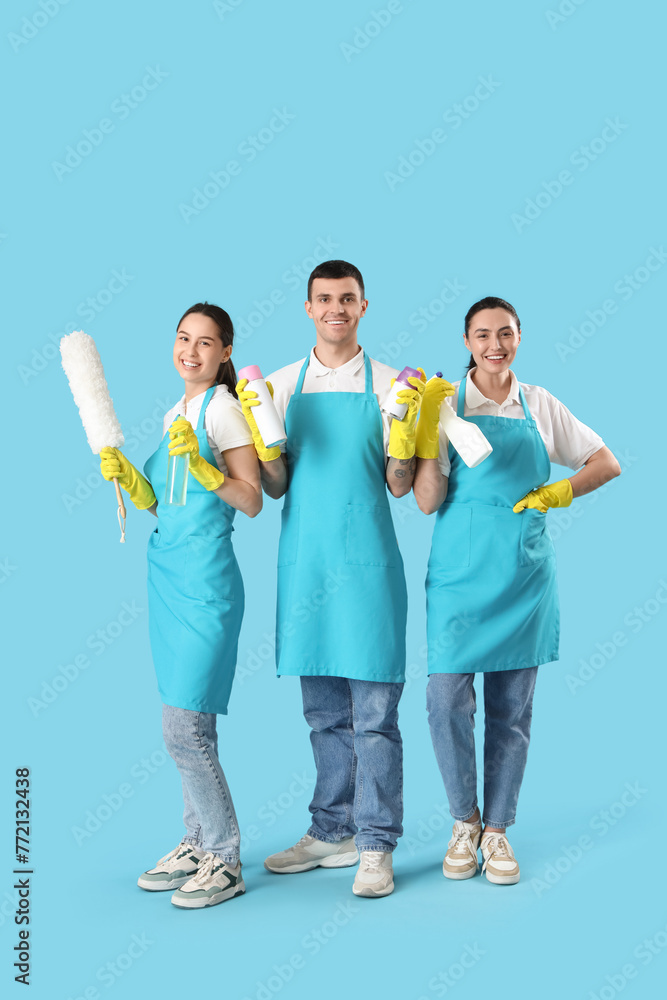 Workers of cleaning service with supplies on blue background