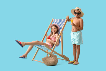 Cute little children in swimsuit, sunglasses with glasses of juice, wicker bag and sun lounger on blue background