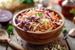 A bowl of coleslaw with carrots and parsley. The bowl is wooden and the food is colorful