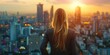 © vefimov - A woman in a suit is looking out over a city at the sun. Concept of ambition and determination, as the woman stands tall and looks out over the urban landscape