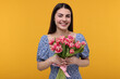 © New Africa - Happy young woman with beautiful bouquet on orange background