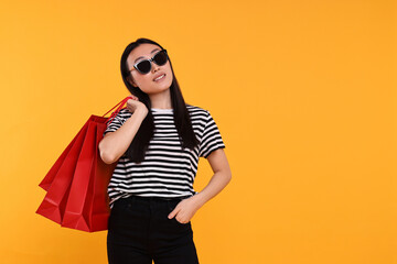 Sticker - Smiling woman with shopping bags on yellow background. Space for text