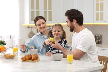 Wall Mural - Happy family having breakfast at table in kitchen