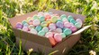 A box filled with colorful Easter eggs sits on a grassy field.