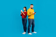 © Prostock-studio - Young Man and Woman Using Smartphones Against Blue Background