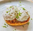 Two poached eggs on brown toast, plated on a white background with chopped chives