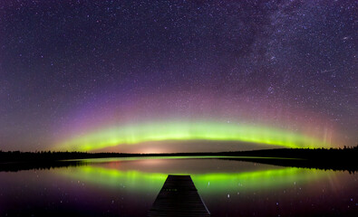 Wall Mural - aurora and stars are reflecting in a northern lake that has a long dock in the foreground. the night