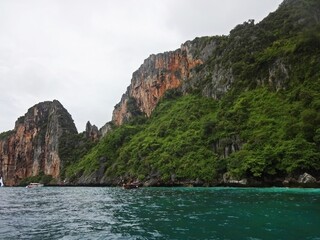 The serene blue sea is complemented by a majestic mountain towering above it, PHI PHI ISLAND, THAILAND 