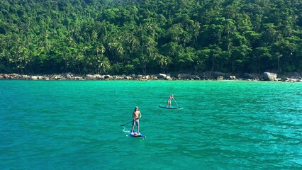 Wall Mural - Drone, people or paddle boarding in ocean with travel for summer with adventure, freedom and tropical vacation. Aerial view, couple or paddleboard with trees, holiday and experience outdoor for relax