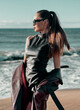 © Subbotina Anna - Beauty Fashion brunette model girl wearing stylish coat and sunglasses, posing on seaside. Sexy glamour woman portrait with perfect makeup, trendy fashion wear. Beauty trends. Fashion blogger.