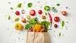 Fresh vegetables falling into the paper bag. vegetables and fruits on white. Shopping food supermarket concept.