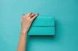 Female hand holding a turquoise clutch on a blue background