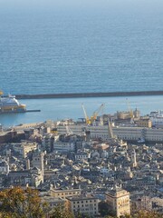 Wall Mural - Genova, Italy - March 24, 2024: Aereal view to the city of Genoa with beautifull blue sea in the background. Sunny spring day over the city. Modern and old architecture mix.