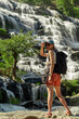 The Asian woman is hiking, and the huge waterfall and my Thailand. Exploring and traveling to Asia concept.