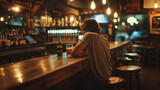 Fototapeta  - A man sits alone at a bar sipping a drink, a glass and bottle on the bar, dim lighting reflecting a mood of loneliness and sadness, an empty stool nearby, a symbol of loss