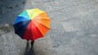 A person protects himself from solar radiation with an umbrella with rainbow colors.
