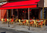 Fototapeta Uliczki - Typical view of street with tables of cafe in Paris, France. Cozy cityscape of Paris. Architecture and landmarks of Paris.